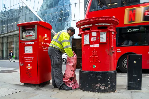 Londra, İngiltere, 11 Temmuz 2023, Modern Ofis Binaları Tarafından Çerçevelenen Geleneksel Kırmızı Posta Kutusundan Posta Topluyor..