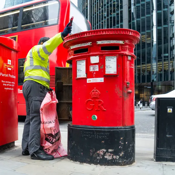Londra, İngiltere, 11 Temmuz 2023, Modern Ofis Binaları Tarafından Çerçevelenen Geleneksel Kırmızı Posta Kutusundan Posta Topluyor..
