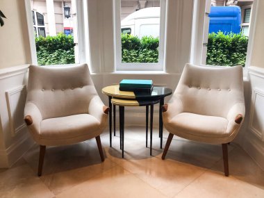 Otel lobisindeki bir sehpanın üzerine yerleştirilmiş bir kitap, sakin ve davetkar bir atmosfer yaratıyor. Yumuşak ışık ve zarif ortam uzayın huzurlu ve rahat atmosferini vurgular..