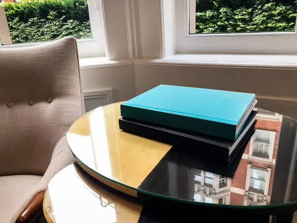 Otel lobisindeki bir sehpanın üzerine yerleştirilmiş bir kitap, sakin ve davetkar bir atmosfer yaratıyor. Yumuşak ışık ve zarif ortam uzayın huzurlu ve rahat atmosferini vurgular..