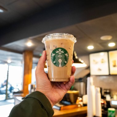 Londra, İngiltere - 12 Temmuz 2023, Dolu Starbucks 'ta Buzlu Kahve İçen Bir El Modern Kafenin İçinde Gündelik Bir Anı Yakalıyor. 