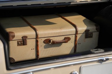 Eski bir araba bagajı, seyahat ve zarafet duygusunu uyandıran klasik bir bavulu ortaya çıkarmak için açıldı. Görüntü, geçmişe dönük otomotiv tasarımı ve nostaljik seyahat elementlerinin karışımını vurgular.