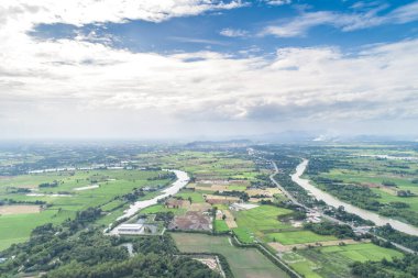 Top view of the Sakae Krang River, Uthai Thani Province where both sides of river are filled with lush green trees. There are community near waterside.