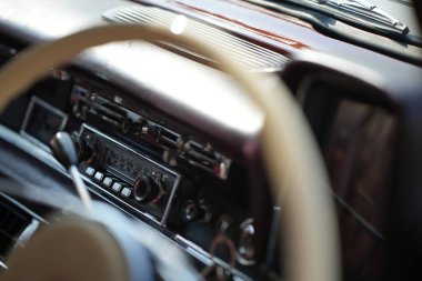 Klasik bir arabanın gösterge panelinde ayrıntılı analog göstergeler, bir radyo ve cilalanmış ahşap ve krom havalandırma delikleri var..