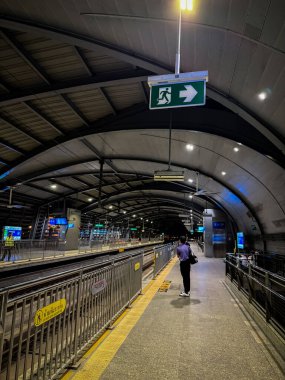 Bangkok, Tayland, 2 Mayıs 2025. Yolcular, Bangkoks Havaalanı Demiryolu 'nun eğimli çelik çatısının altında, Lat Krabang İstasyonu' ndaki platformun kenarında duruyorlar.. 