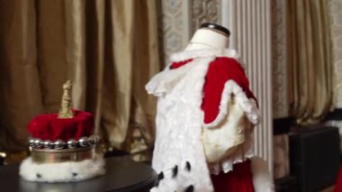 Kadife bir taç ve kraliyet cübbesi sergilenmekte, monarşiyi, otoriteyi ve kralların ve kraliçelerin ebedi mirasını sembolize ediyor..