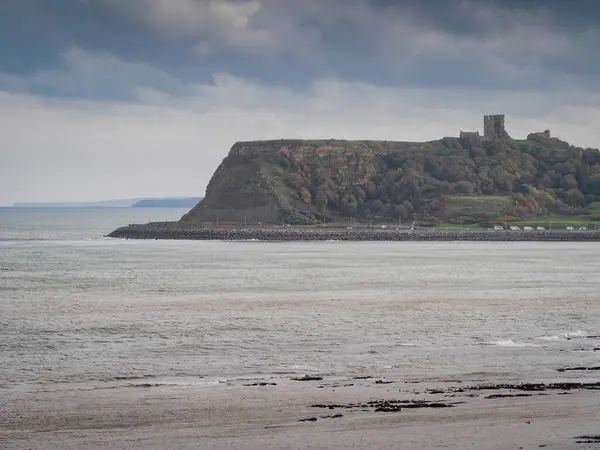 stock image View from Scalby Mills across North Bay and Marine Drive to the ruins of Scarborough Castle on top of the cliffs under a moody sky, Scarborough, North Yorkshire, UK