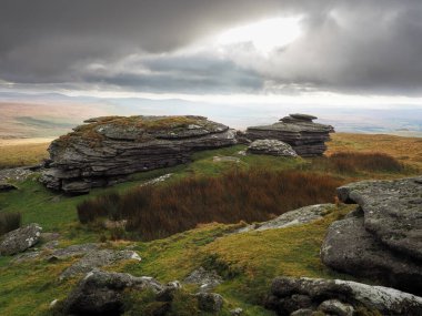 Devon kırsalındaki Great Links Tor 'dan bulutlar dağılmaya ve tepelere vuran güneş ışınları, Dartmoor Ulusal Parkı, Devon, İngiltere