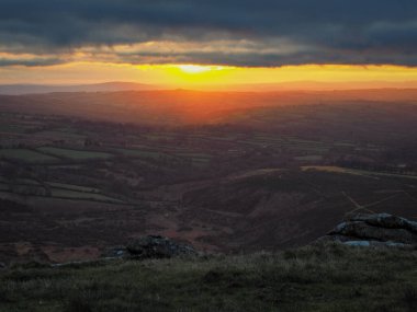 Brats Tor 'dan gün batımına doğru Brent Tor' un tepesindeki St. Michael de Rupe kilisesi ile kuzey Devon 'a bakan Dartmoor Ulusal Parkı, Devon, İngiltere