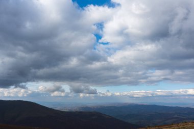 Yeşil çayırlar, ağaçlar, arka planda dağlarda koyu alçak bulutlar olan Karpatya yaban örümceğinin güzel manzarası. Seyahat yerleri. Sonbahar manzarası. 