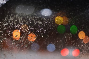 Yağmur damlaları ve ışıklarla bulanık arkaplan.