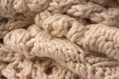 A fragment of beige knitted fabric, knitted from white sheep wool. Knitted background. 