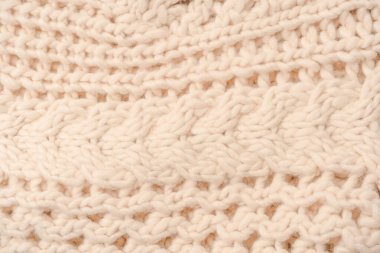 A fragment of beige knitted fabric, knitted from white sheep wool. Knitted background. 