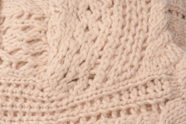 A fragment of beige knitted fabric, knitted from white sheep wool. Knitted background. 