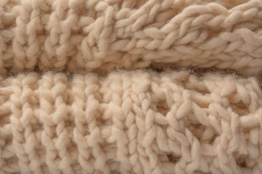 A fragment of beige knitted fabric, knitted from white sheep wool. Knitted background. 