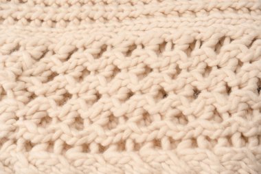 A fragment of beige knitted fabric, knitted from white sheep wool. Knitted background. 