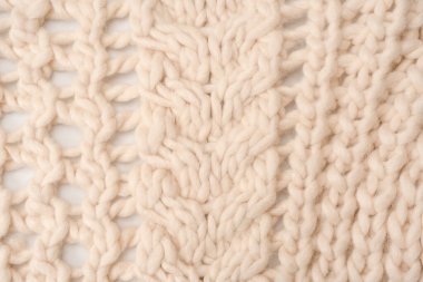 A fragment of beige knitted fabric, knitted from white sheep wool. Knitted background. 
