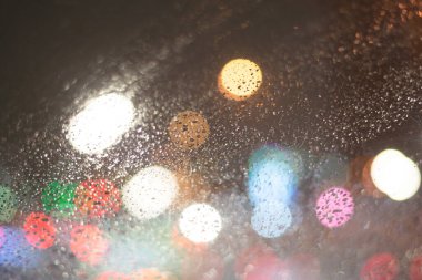 Yağmur damlaları ve ışıklarla bulanık arkaplan.