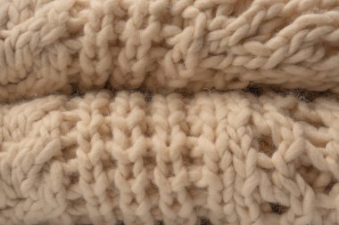 A fragment of beige knitted fabric, knitted from white sheep wool. Knitted background. 