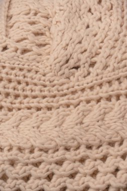 A fragment of beige knitted fabric, knitted from white sheep wool. Knitted background. 