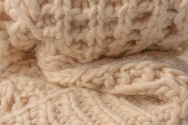 A fragment of beige knitted fabric, knitted from white sheep wool. Knitted background. 