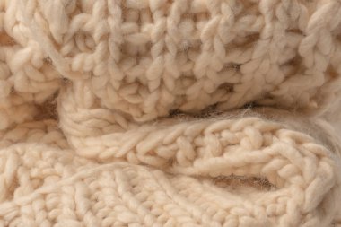 A fragment of beige knitted fabric, knitted from white sheep wool. Knitted background. 