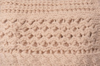 A fragment of beige knitted fabric, knitted from white sheep wool. Knitted background. 