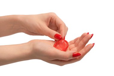 Beyaz arka planda kırmızı tırnaklı bir kadın elinde kırmızı bir prezervatif.. 