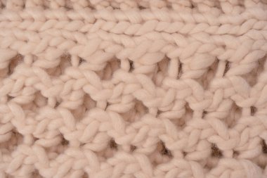 A fragment of beige knitted fabric, knitted from white sheep wool. Knitted background. 