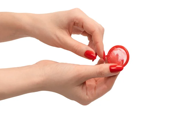stock image A red condom in a woman hand with red nails isolated on a white background. 