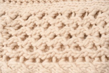 A fragment of beige knitted fabric, knitted from white sheep wool. Knitted background. 