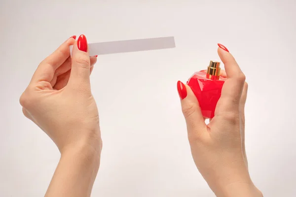 Stock image Woman hand with red nails with test strips for the perfume, isolated on a white background. Perfume blotters.