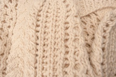 A fragment of beige knitted fabric, knitted from white sheep wool. Knitted background. 