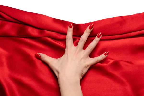 A woman's hand with red nails is trying to rip off  red silk fabric.