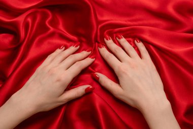Kırmızı tırnaklı bir kadının eli kırmızı ipek kumaşı yırtmaya çalışıyor.. 