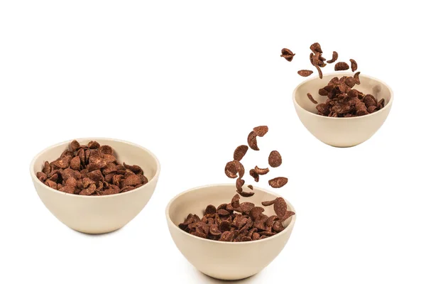 stock image Chocolate corn flakes falling to the white bowl isolated on white. Motion. Copyspace.