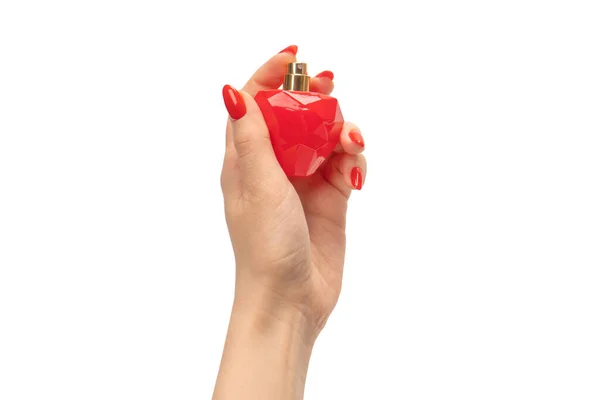 Red bottle of perfume in woman hand with red nails isolated on a white background. Applying perfume.