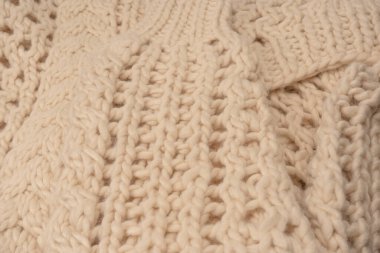A fragment of beige knitted fabric, knitted from white sheep wool. Knitted background. 