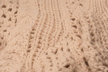 A fragment of beige knitted fabric, knitted from white sheep wool. Knitted background. 