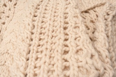 A fragment of beige knitted fabric, knitted from white sheep wool. Knitted background. 