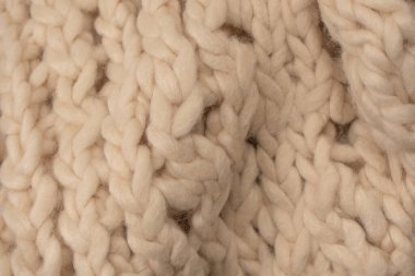 A fragment of beige knitted fabric, knitted from white sheep wool. Knitted background. 