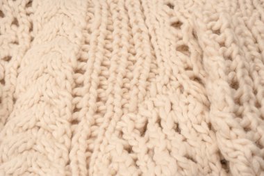 A fragment of beige knitted fabric, knitted from white sheep wool. Knitted background. 