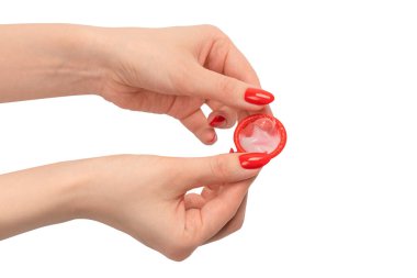 Beyaz arka planda kırmızı tırnaklı bir kadın elinde kırmızı bir prezervatif.. 