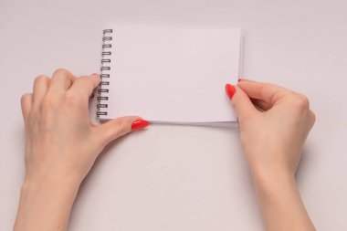 Kırmızı tırnaklı kadınların elinde boş beyaz kağıt olan bir defter. Boşluğu kopyala. 