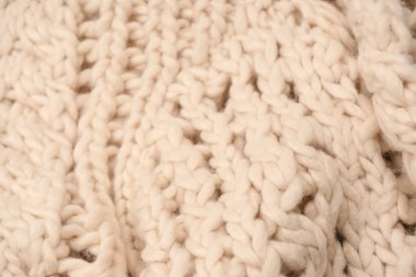 A fragment of beige knitted fabric, knitted from white sheep wool. Knitted background. 