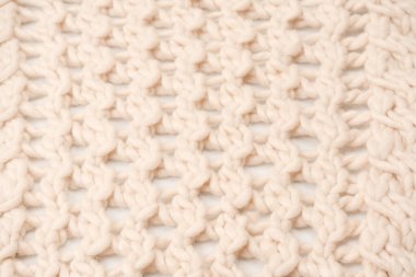 A fragment of beige knitted fabric, knitted from white sheep wool. Knitted background. 