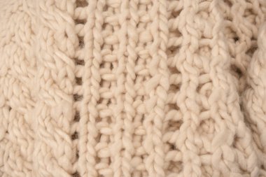 A fragment of beige knitted fabric, knitted from white sheep wool. Knitted background. 