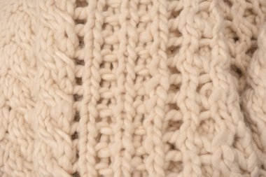 A fragment of beige knitted fabric, knitted from white sheep wool. Knitted background. 