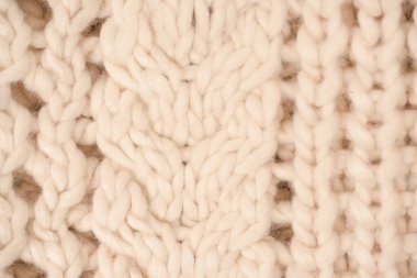 A fragment of beige knitted fabric, knitted from white sheep wool. Knitted background. 