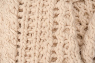 A fragment of beige knitted fabric, knitted from white sheep wool. Knitted background. 